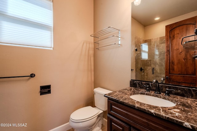 bathroom with a stall shower, baseboards, vanity, and toilet