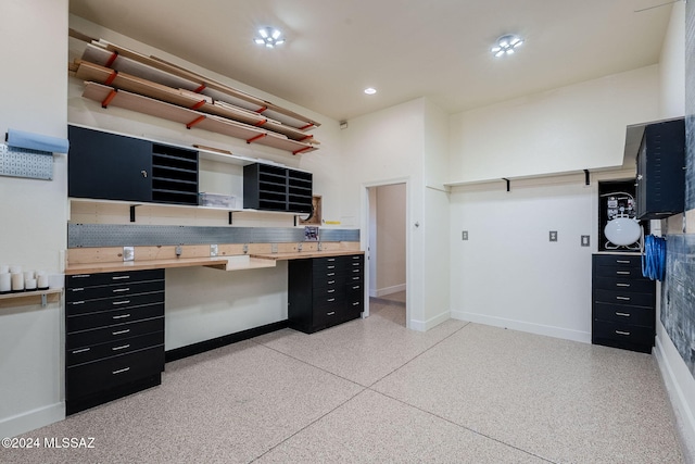 kitchen featuring light speckled floor, open shelves, dark cabinetry, and baseboards