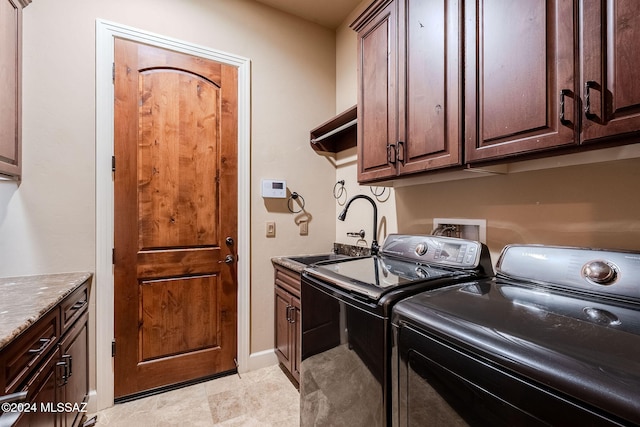 clothes washing area featuring separate washer and dryer, a sink, cabinet space, and baseboards