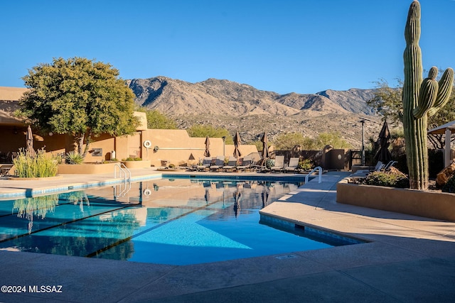 community pool with a mountain view, a patio, and fence