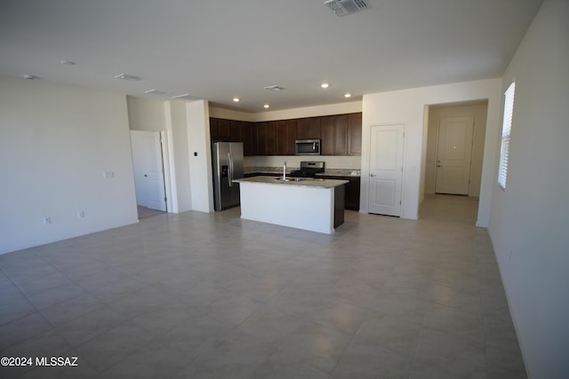 kitchen featuring dark brown cabinets, stainless steel appliances, a center island with sink, and sink