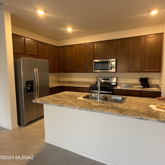 kitchen featuring light stone countertops, sink, dark brown cabinetry, and stainless steel appliances