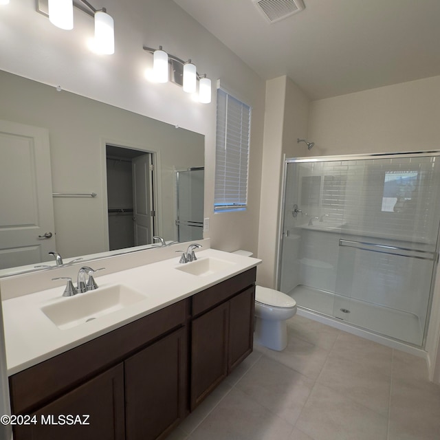 bathroom with toilet, vanity, tile patterned flooring, and a shower with door