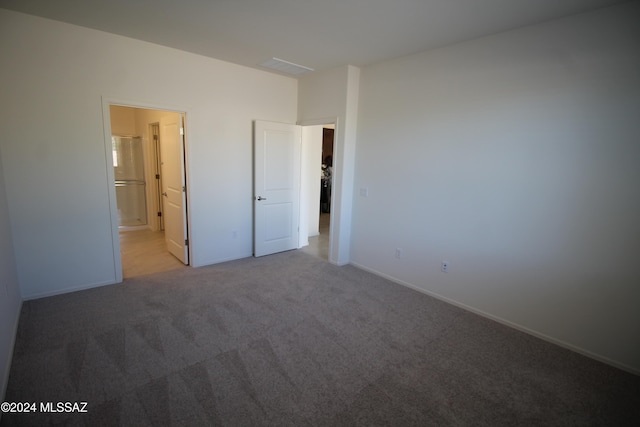 unfurnished bedroom with light carpet and connected bathroom