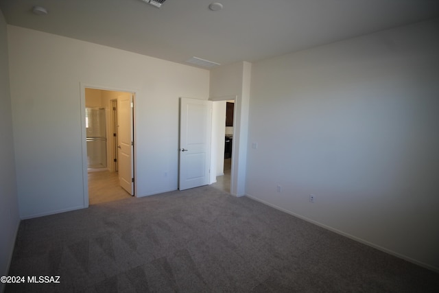 unfurnished bedroom with ensuite bath and light carpet