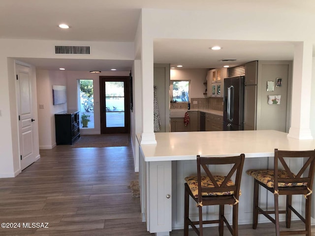 kitchen with gray cabinetry, dark hardwood / wood-style flooring, kitchen peninsula, high quality fridge, and a breakfast bar area