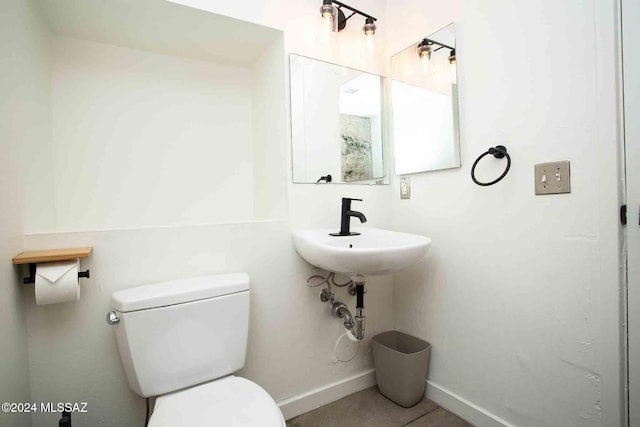 bathroom featuring toilet, sink, and tile patterned flooring