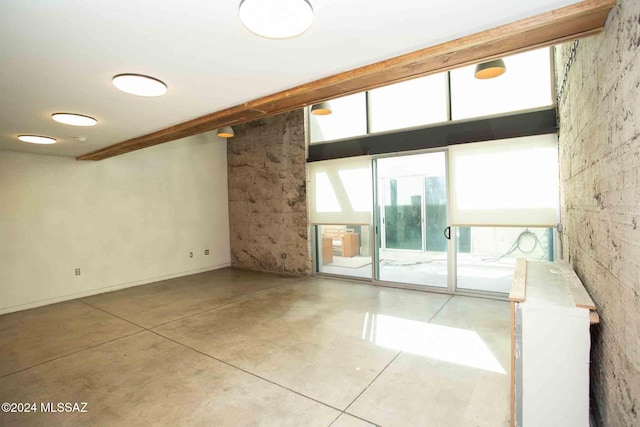 spare room featuring beamed ceiling and concrete flooring