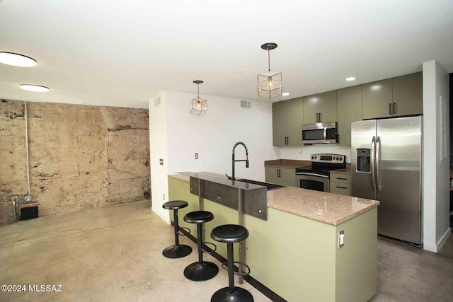 kitchen featuring hanging light fixtures, appliances with stainless steel finishes, a breakfast bar, concrete flooring, and sink