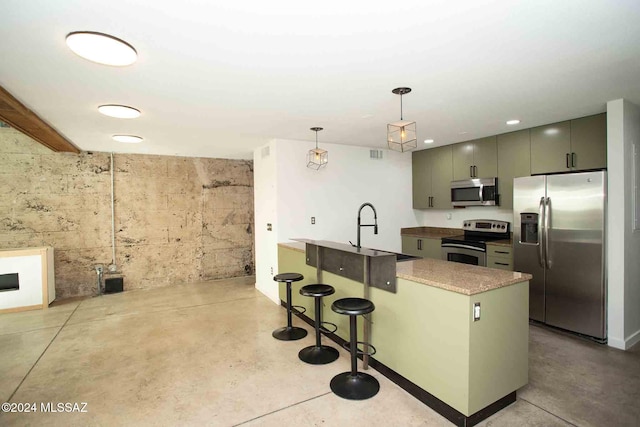 kitchen featuring kitchen peninsula, sink, a breakfast bar, pendant lighting, and appliances with stainless steel finishes