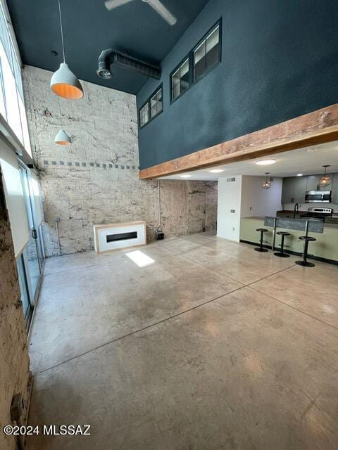 interior space featuring concrete floors, a high ceiling, and a wealth of natural light