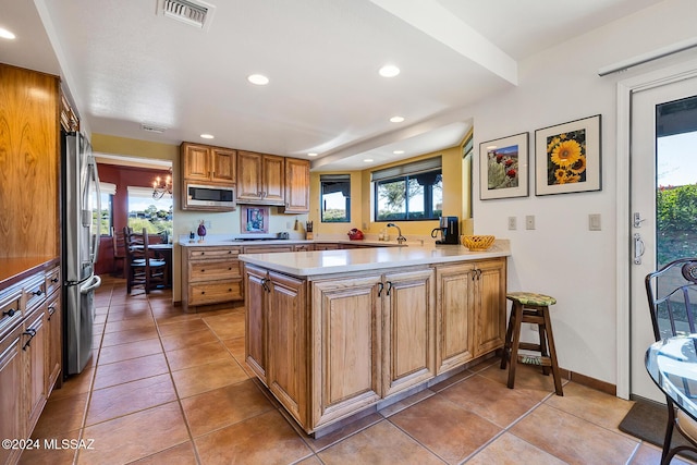 kitchen with light tile patterned floors, kitchen peninsula, and appliances with stainless steel finishes