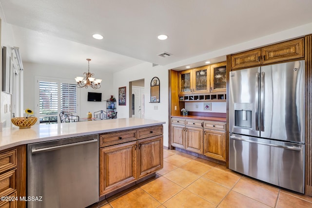 kitchen with hanging light fixtures, appliances with stainless steel finishes, light tile patterned floors, and a notable chandelier