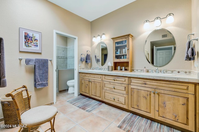 bathroom with vanity, tiled shower, tile patterned floors, and toilet