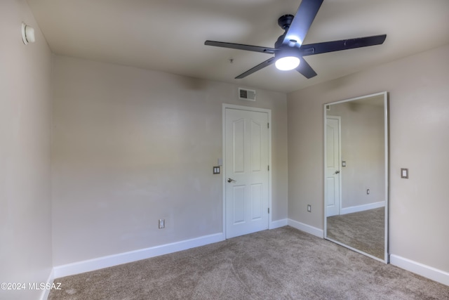 unfurnished bedroom featuring light colored carpet, a closet, and ceiling fan