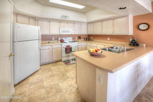 kitchen with white appliances, a raised ceiling, sink, a textured ceiling, and kitchen peninsula