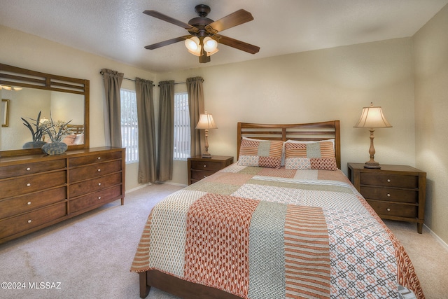 bedroom with ceiling fan, light colored carpet, and a textured ceiling