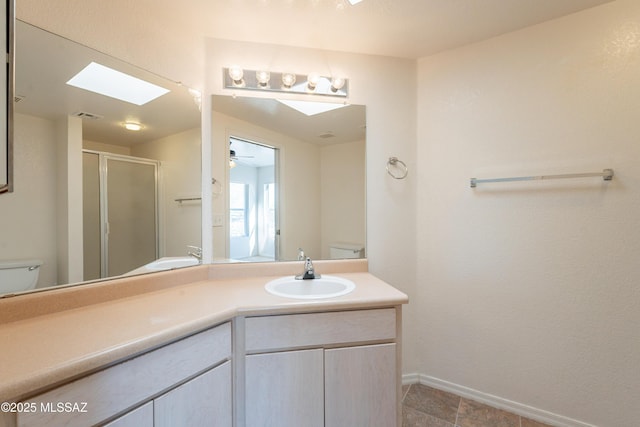 bathroom featuring a skylight, vanity, a shower stall, and toilet