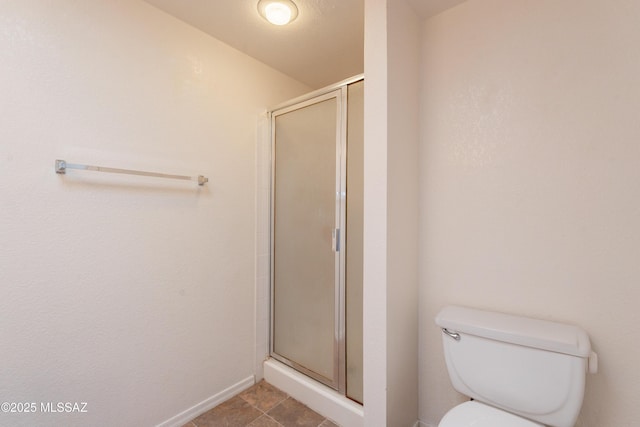 full bath featuring baseboards, a stall shower, and toilet