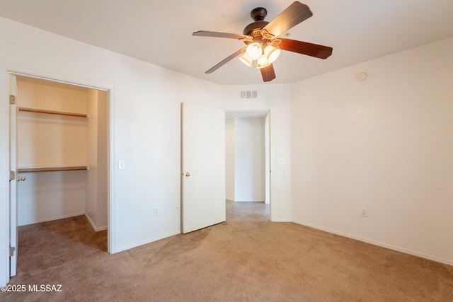 unfurnished bedroom featuring a walk in closet, carpet floors, baseboards, visible vents, and a closet