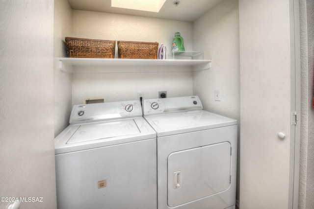 clothes washing area with a skylight and washer and clothes dryer