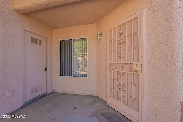 property entrance featuring visible vents and stucco siding