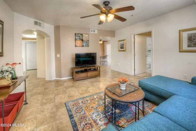 living room with a textured ceiling and ceiling fan