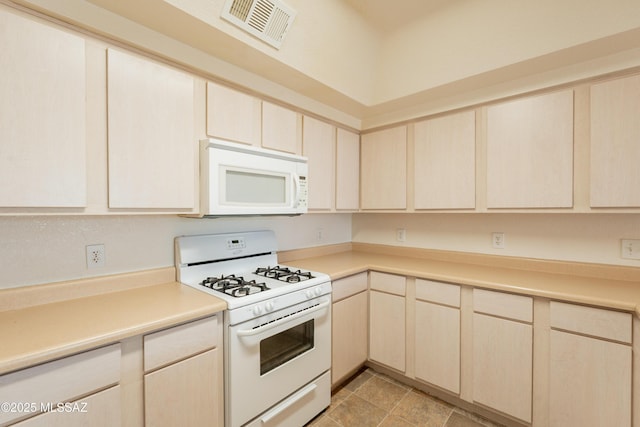 kitchen with light countertops, light brown cabinets, white appliances, and visible vents