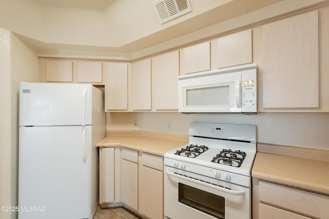 kitchen featuring visible vents, light countertops, light brown cabinets, and white appliances