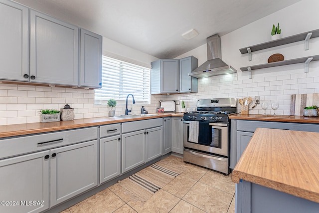 kitchen with wall chimney exhaust hood, stainless steel gas range oven, sink, and wooden counters