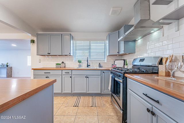 kitchen with sink, stainless steel gas stove, wall chimney range hood, wood counters, and backsplash