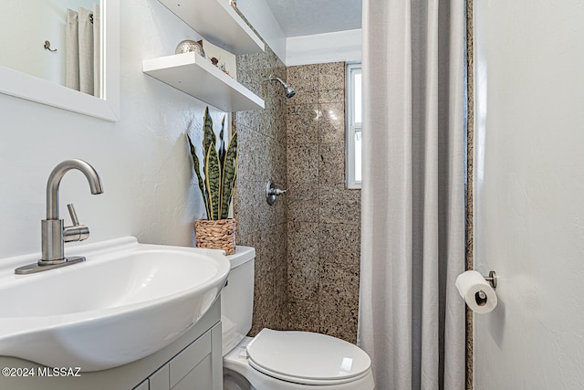 bathroom with tiled shower, a textured ceiling, vanity, and toilet