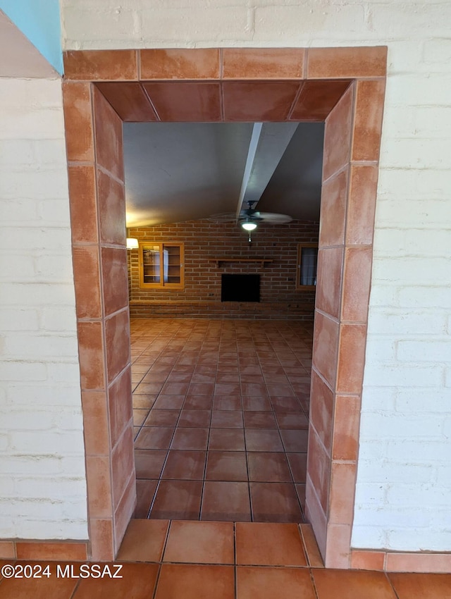 corridor with tile patterned flooring, brick wall, and vaulted ceiling with beams