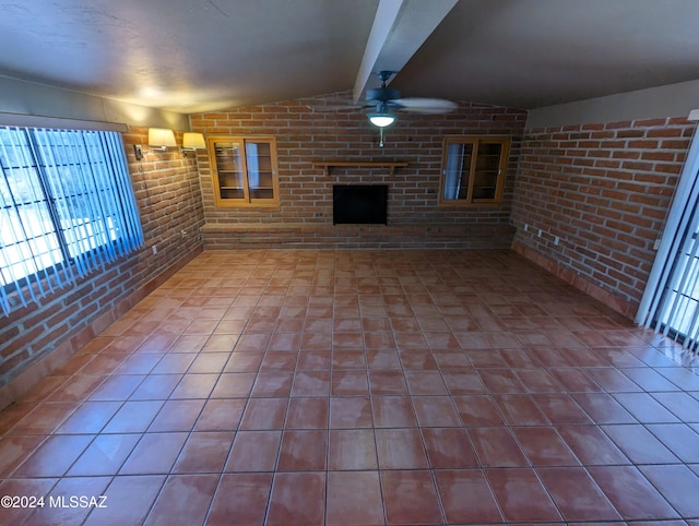 unfurnished living room featuring lofted ceiling with beams, brick wall, and ceiling fan