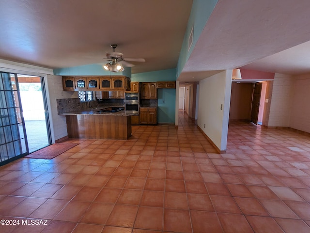 kitchen with kitchen peninsula, ceiling fan, vaulted ceiling, and stainless steel double oven