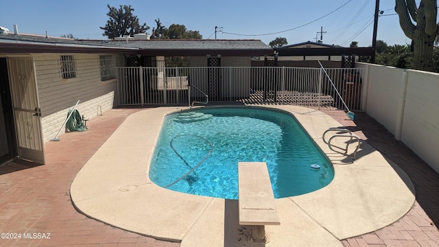 view of pool with a diving board and a patio area