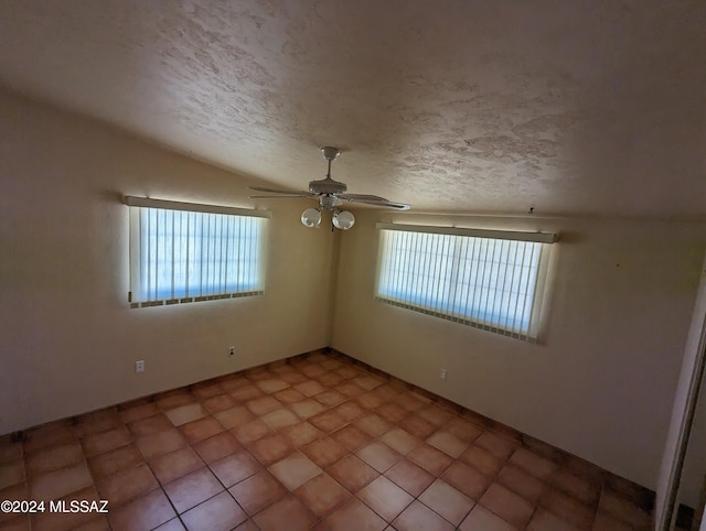 tiled empty room featuring a textured ceiling, ceiling fan, and vaulted ceiling