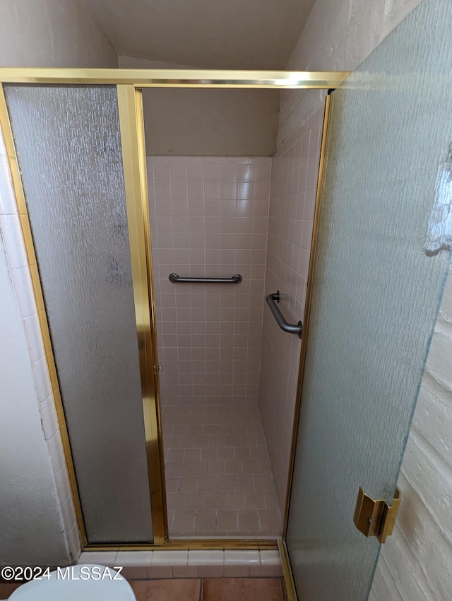 bathroom with a shower with shower door and toilet