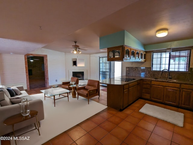 kitchen featuring tasteful backsplash, sink, a brick fireplace, kitchen peninsula, and ceiling fan