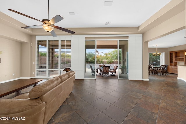 unfurnished living room featuring ceiling fan with notable chandelier and plenty of natural light