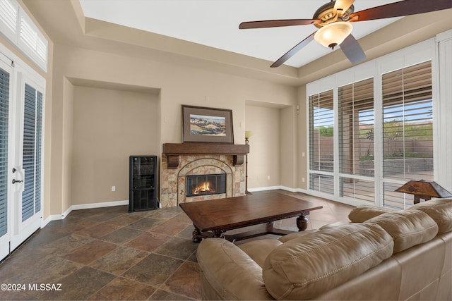 living room featuring ceiling fan and a stone fireplace