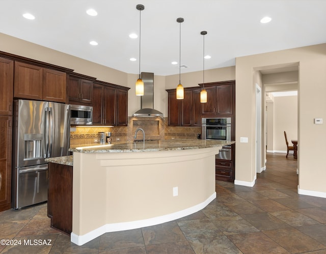 kitchen featuring wall chimney exhaust hood, hanging light fixtures, light stone counters, decorative backsplash, and appliances with stainless steel finishes