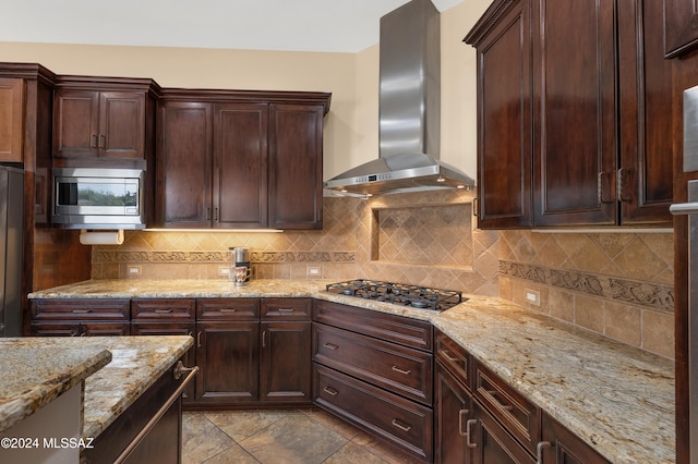 kitchen featuring light stone countertops, appliances with stainless steel finishes, tasteful backsplash, and wall chimney range hood