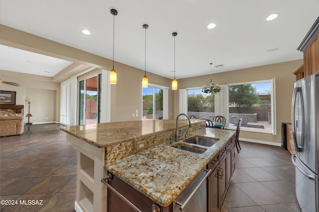 kitchen with appliances with stainless steel finishes, a center island with sink, decorative light fixtures, and sink