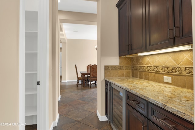 kitchen featuring dark brown cabinetry, tasteful backsplash, light stone counters, and beverage cooler