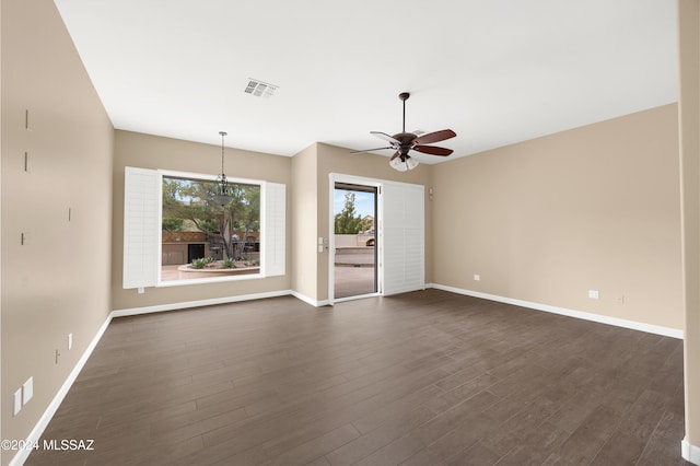 spare room featuring dark hardwood / wood-style floors and ceiling fan with notable chandelier