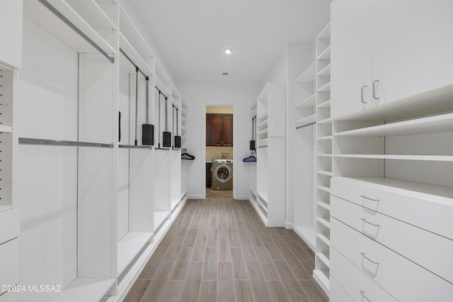 walk in closet with washer / clothes dryer and light wood-type flooring