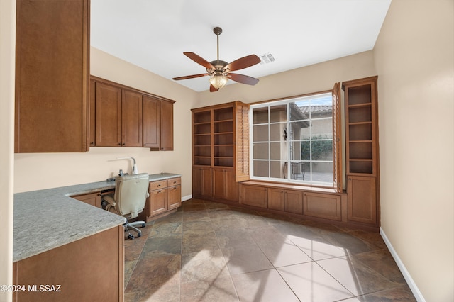 unfurnished office featuring ceiling fan and built in desk