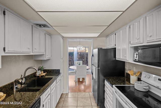 kitchen featuring dark stone counters, sink, black appliances, light tile patterned floors, and white cabinets