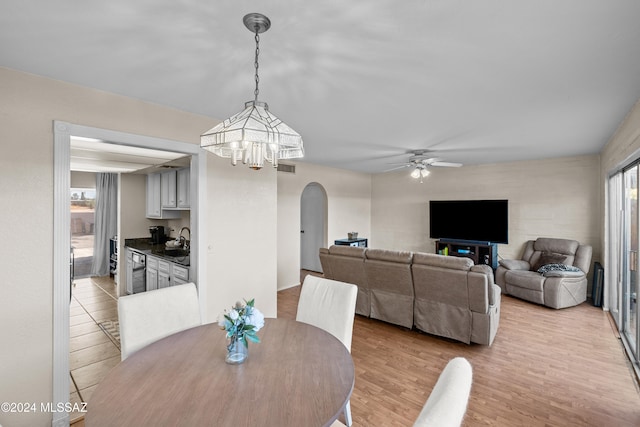 dining area with sink, light hardwood / wood-style floors, and ceiling fan with notable chandelier